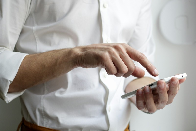 Pessoa conversando por aplicativo de mensagens no celular, apoiada em uma mesa de trabalho