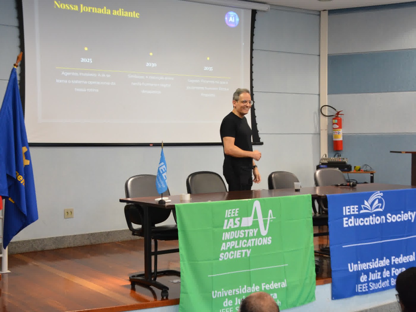 Marcos Alves, CEO da Hal-AI, durante a palestra no ENTENSE 2026, no anfiteatro da UFJF, diante dos banners do IEEE IAS e da IEEE Education Society.